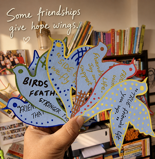 A handmade Joy Box tied with a clay-coloured ribbon beside painted bookmarks and wooden pieces